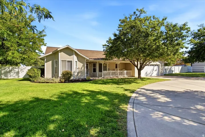 Single-story residence featuring light-toned siding, a covered front porch with white railing, and an attached two-car garage