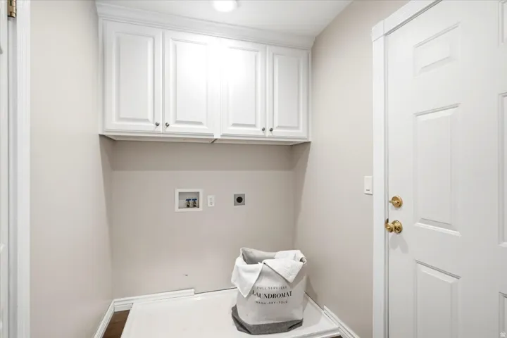 White shaker-style cabinetry with crown molding, recessed lighting, and a paneled interior door with brass hardware