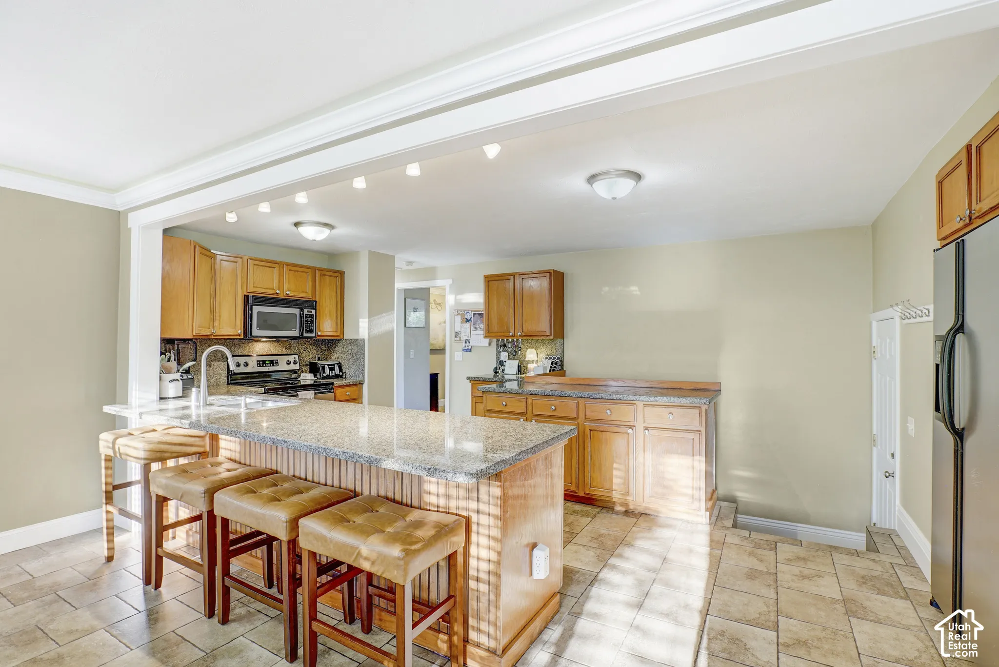 Kitchen featuring wood cabinetry, stone-finish countertops, stainless steel appliances, tile flooring, and recessed lighting