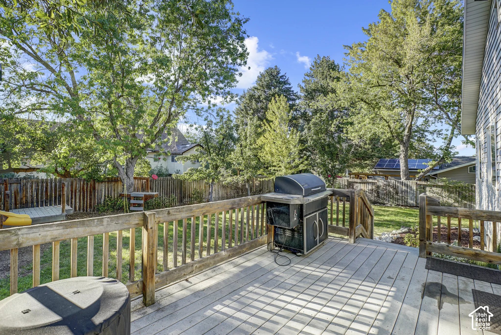 Expansive wooden deck with railing, stairs, and surrounding mature trees
