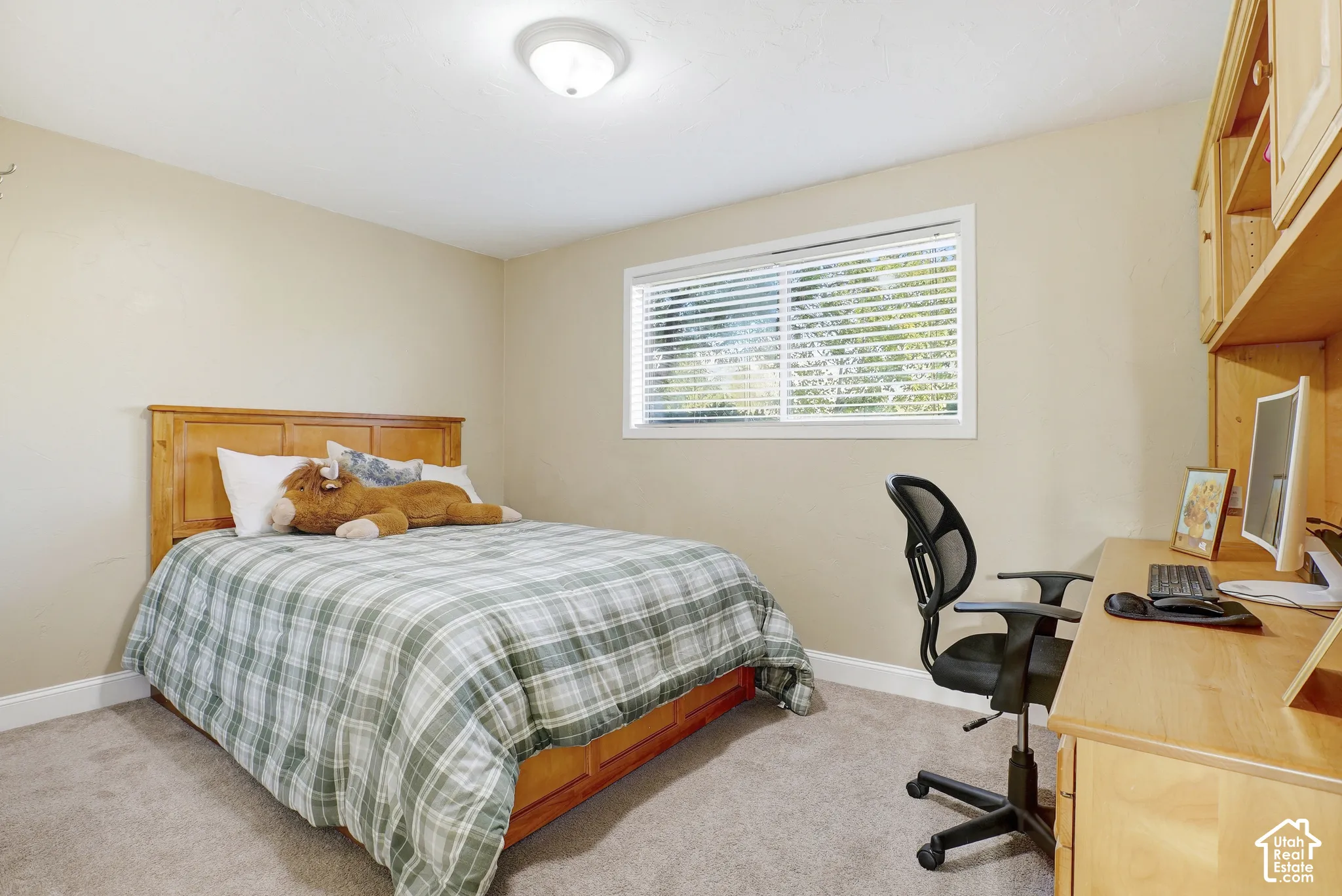 Built-in wood-finish shelving, wood-finish desk, wood-finish bed frame, horizontal window, and flush-mount ceiling light