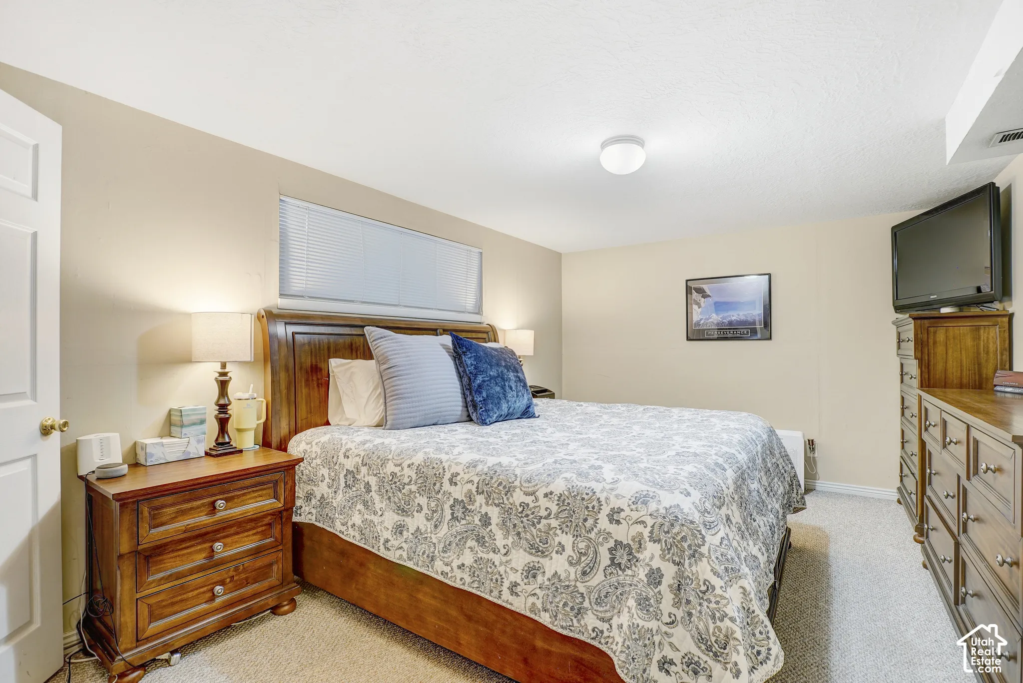 Carpeted room with a wall-mounted window, cream-colored walls, and a ceiling-mounted light fixture