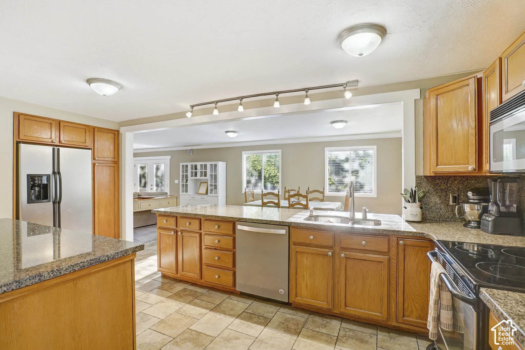 Kitchen featuring wood cabinetry, granite-finish countertops, stainless steel appliances, and tiled flooring