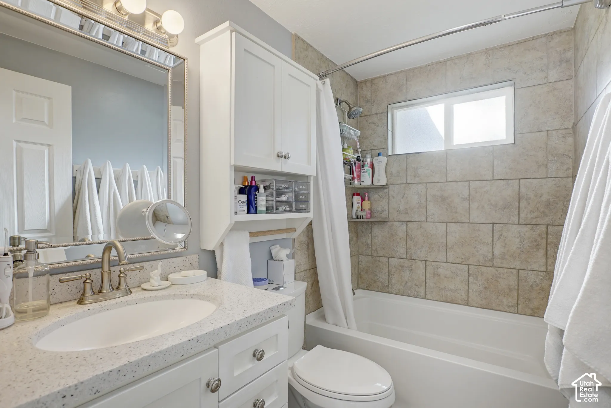 Bathroom featuring a white vanity with an integrated oval sink, a speckled countertop, and a brushed nickel faucet