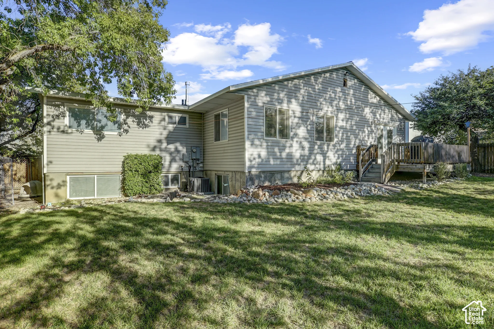 Expansive backyard with a manicured lawn, established landscaping, and a multi-level wood deck