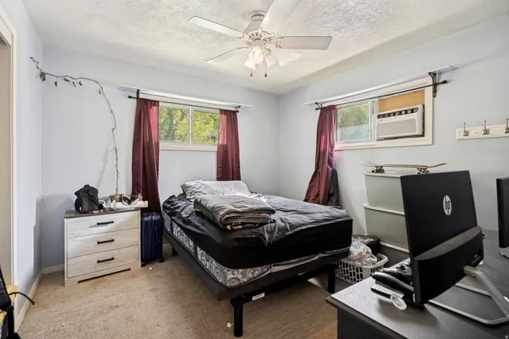 Recessed window with an installed air conditioning unit, ceiling fan with integrated lighting, and wall-mounted coat hooks