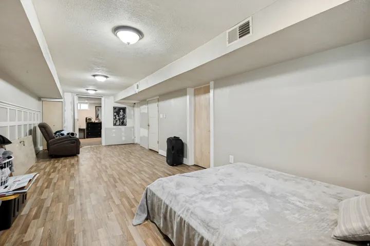 Recessed ceiling, wood-finish flooring, white paneled wall detail, multiple flush-mount light fixtures, and neutral wall paint