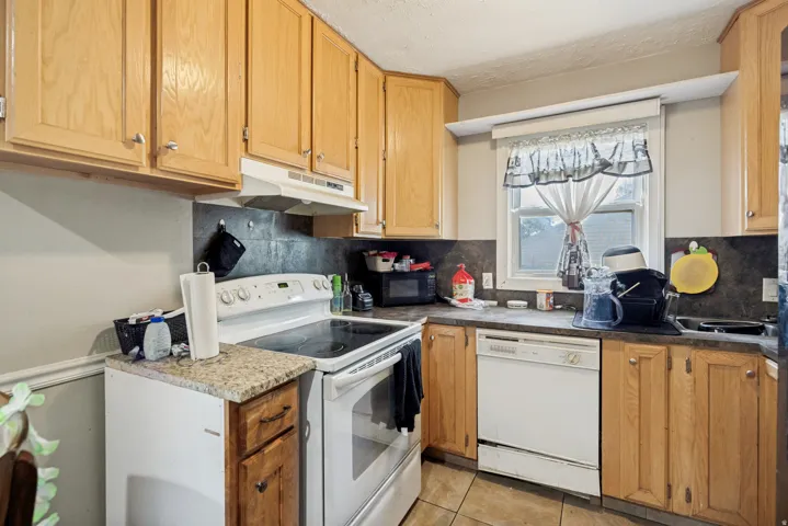 Kitchen featuring wood-finish cabinetry, a white electric range, and a white dishwasher