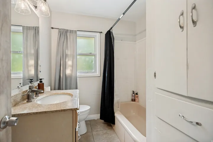 Vanity with integrated sink and stone countertop, illuminated by a multi-bulb light fixture