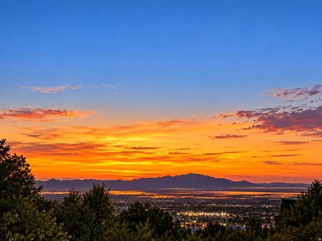 Scenic mountain backdrop with a vibrant sky and distant city lights