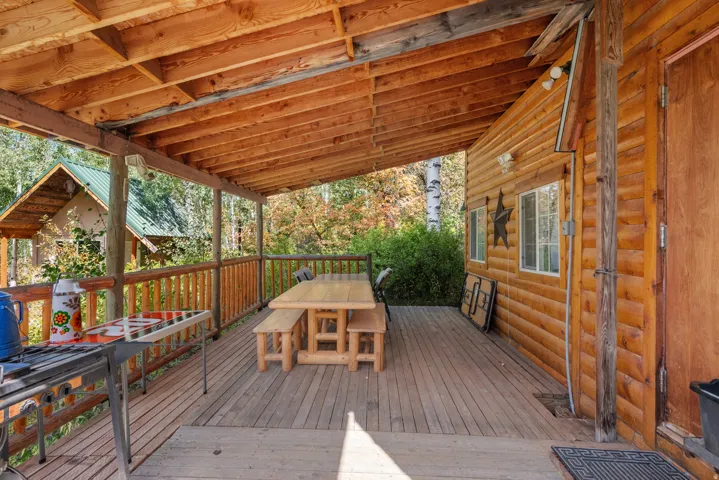Expansive wood deck with a full overhead covering, log-style railings, and natural wood siding