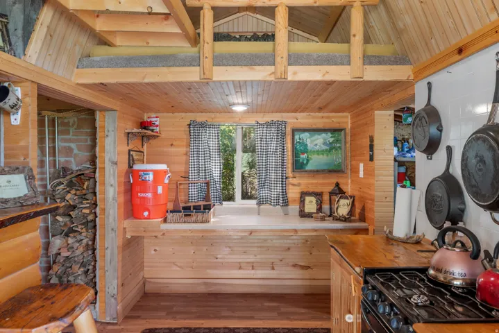 Wood-paneled interior featuring a built-in loft, kitchen counter with a gas range, and a stone-clad alcove
