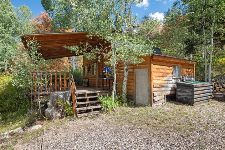 Log cabin exterior featuring a covered porch, wood-plank decking, and natural wood railings