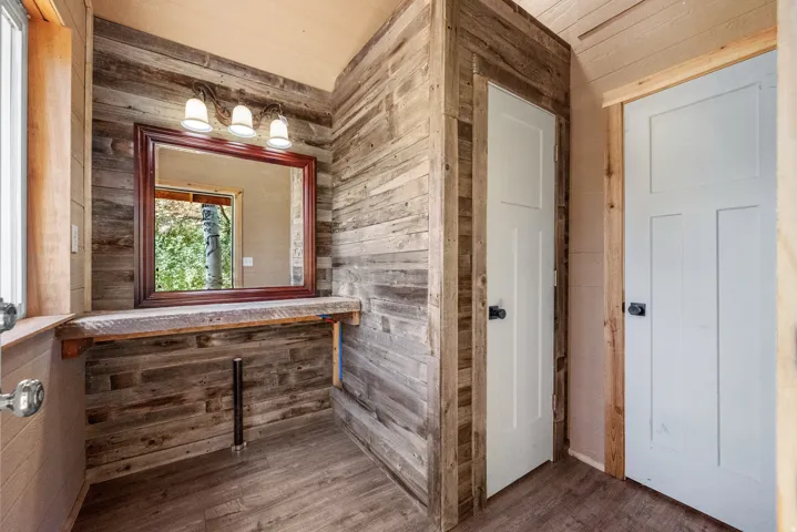 Wood-finish wall paneling, built-in vanity, framed mirror, three-light vanity fixture, and paneled interior doors