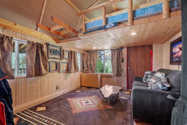 Wood-paneled walls and ceiling with recessed lighting, exposed wood beams, and a wood-finish door