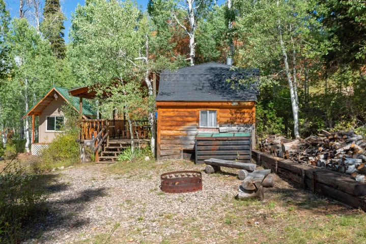 Two cabins, one with a covered porch and wood railings, the other with log siding and a small window