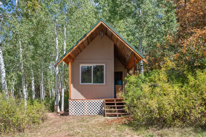 Compact structure featuring a gabled roof, natural wood soffit, and horizontal siding