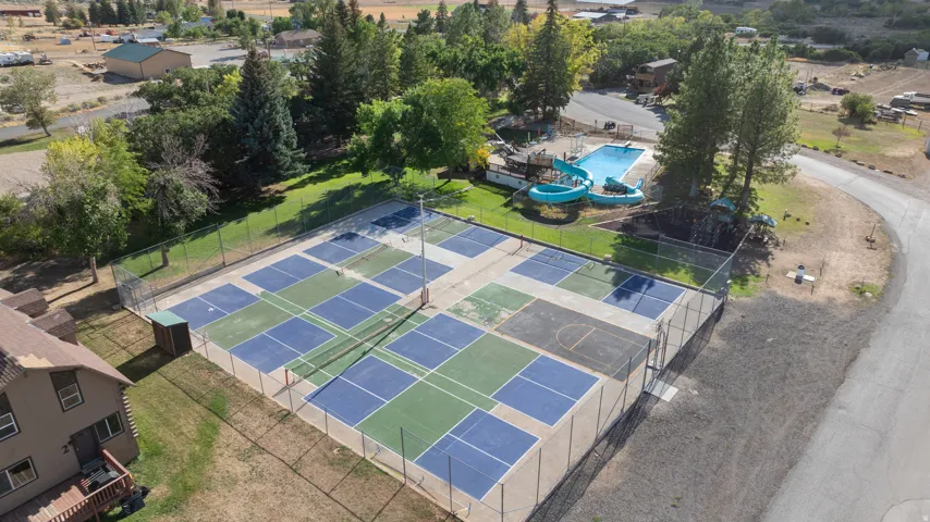 Outdoor recreational area featuring multiple courts, swimming pool with slides, and mature trees