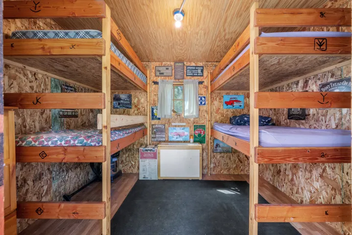 Built-in wooden bunk beds, wood-finish flooring, textured wall panels, and a ceiling-mounted light fixture