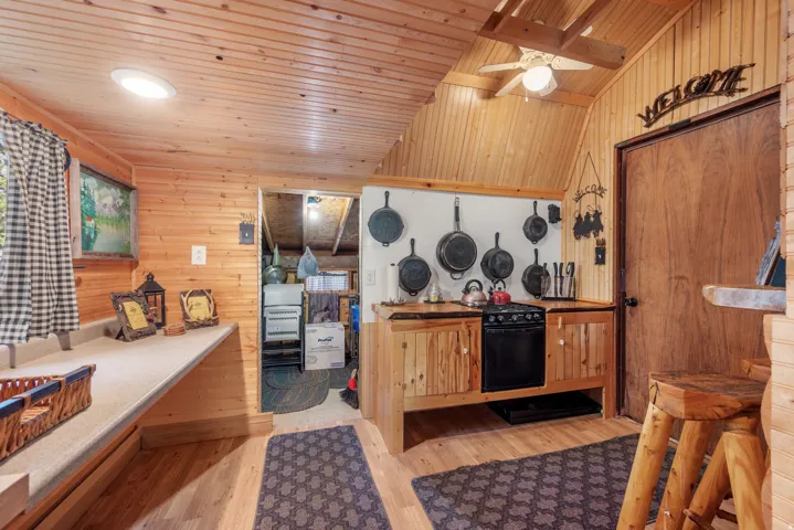 Wood-paneled walls and ceiling, a built-in countertop with shelving, integrated range with oven, and wood-finish flooring