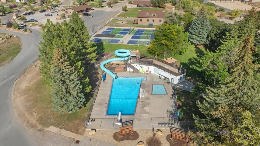 Outdoor swimming pool with a water slide, adjacent spa, and surrounding paved deck