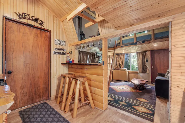 Full wood-finish wall and ceiling paneling, wood-finish flooring, and a built-in bar with a solid wood-finish top