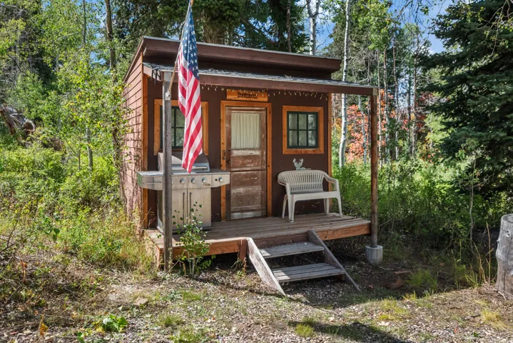 Wood-sided structure featuring a covered porch, wood-plank decking, and a built-in outdoor cooking area