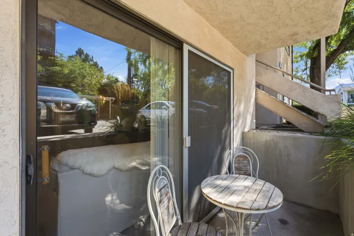 Patio area featuring a stucco exterior, concrete flooring, and a large sliding glass door with a screen