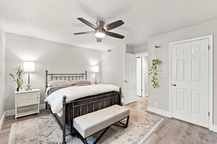 Wood-finish flooring, ceiling fan with integrated lighting, two white panel doors, and neutral wall paint