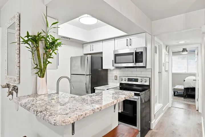 Kitchen with white cabinetry, stainless steel appliances, white subway tile backsplash, and light-toned countertop