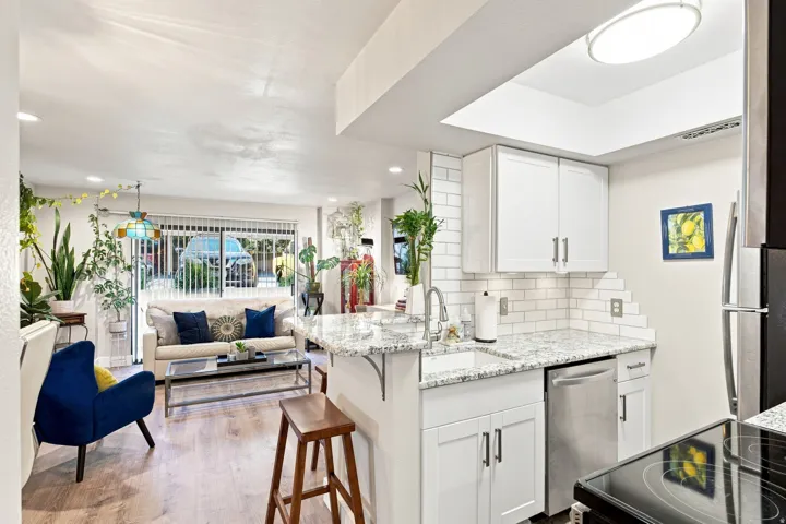 Kitchen featuring white cabinetry with silver hardware, white subway tile backsplash, and light-toned countertop