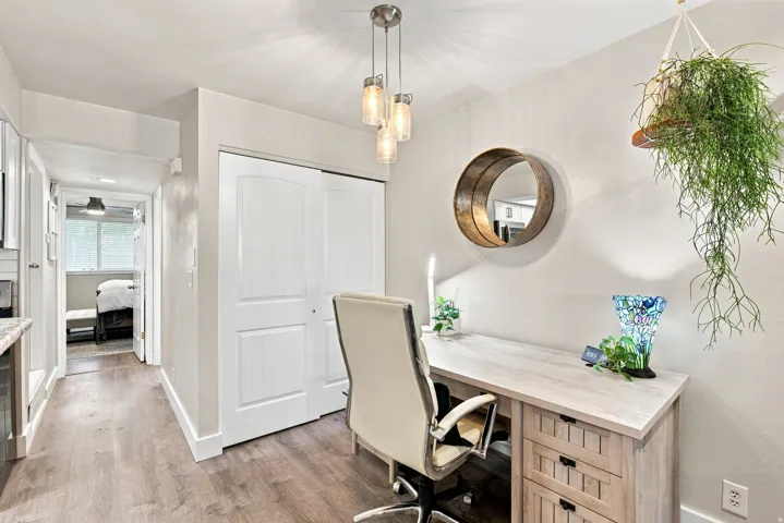 Wood-finish flooring throughout, white interior doors, and a built-in desk with cabinet storage