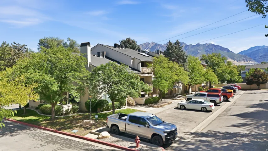 Multi-level residential building with balconies, mature trees, and landscaping