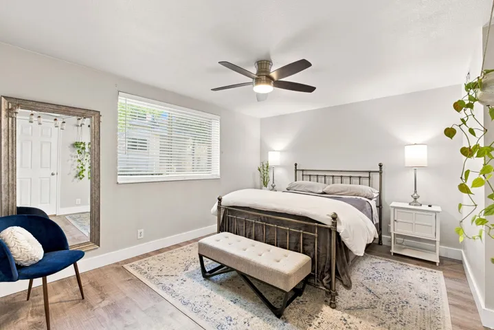 Wood-finish flooring, ceiling fan with integrated lighting, and a window with blinds