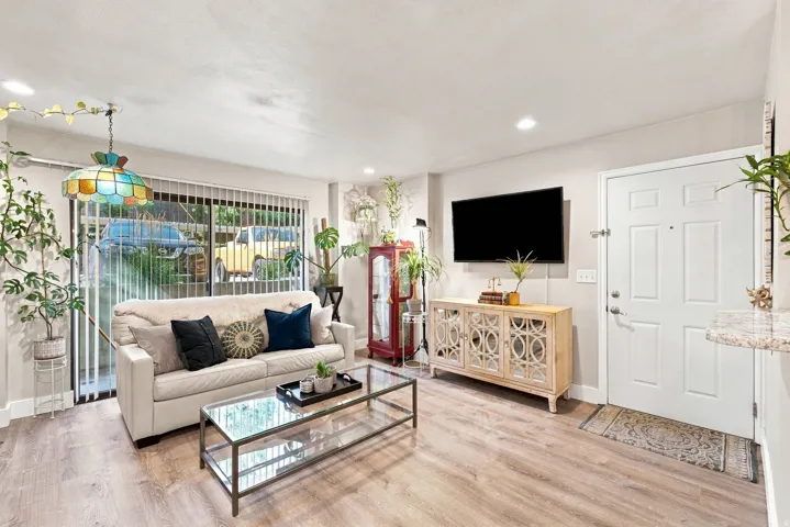 Wood-finish flooring, recessed lighting, and sliding glass doors with vertical blinds