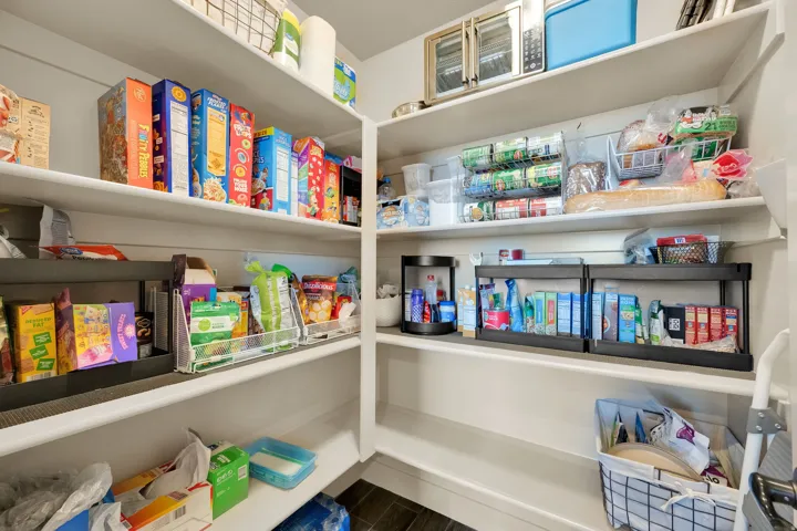 Built-in pantry shelving system with white finishes and dark wood-finish flooring