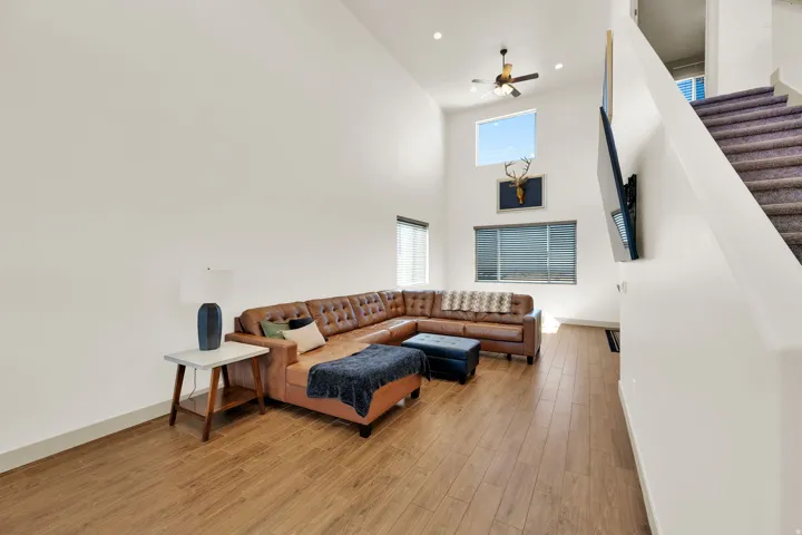 Vaulted ceiling with a ceiling fan, recessed lighting, and wood-finish flooring