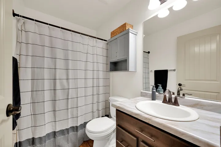 Vanity with an integrated sink, wood-finish cabinetry, and a large wall mirror