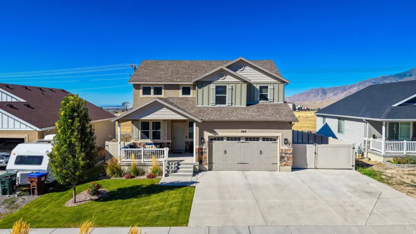 Two-story residence featuring a two-car garage, concrete driveway, covered porch with white railing, and a fenced side yard