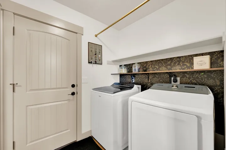 White panel door with black hardware, upper storage shelf, wood-finish shelving, and a gold-finish hanging rod