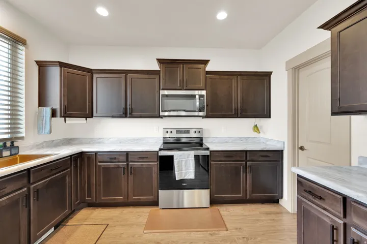 Kitchen with dark wood-finish cabinetry, light-toned countertops, and wood-finish flooring