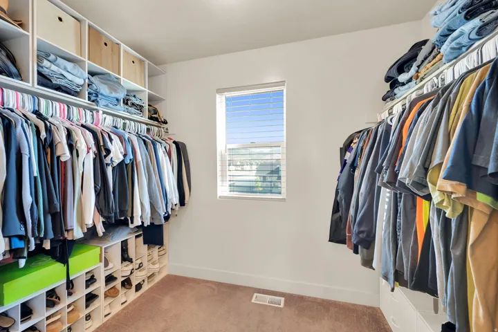 Walk-in closet featuring extensive built-in shelving, integrated hanging rods, and a window with blinds