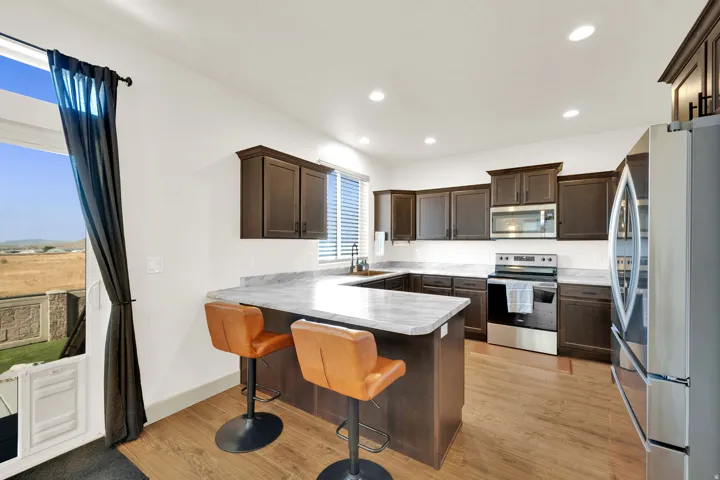 Kitchen featuring wood-finish flooring, dark wood cabinetry, light countertops, and stainless steel appliances
