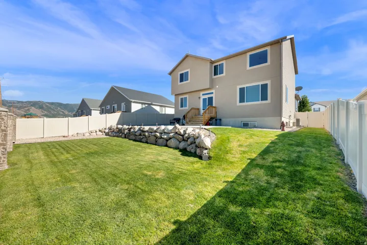 Expansive lawn area with a rock retaining wall and surrounding fencing