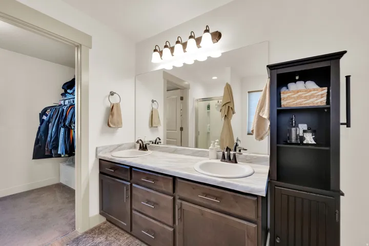 Dual vanity with undermount sinks, wood-finish cabinetry, and a large wall-mounted mirror