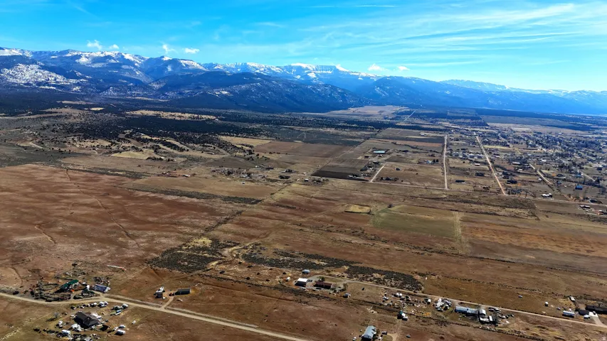 Expansive undeveloped terrain with distant snow-capped mountains and scattered residential structures