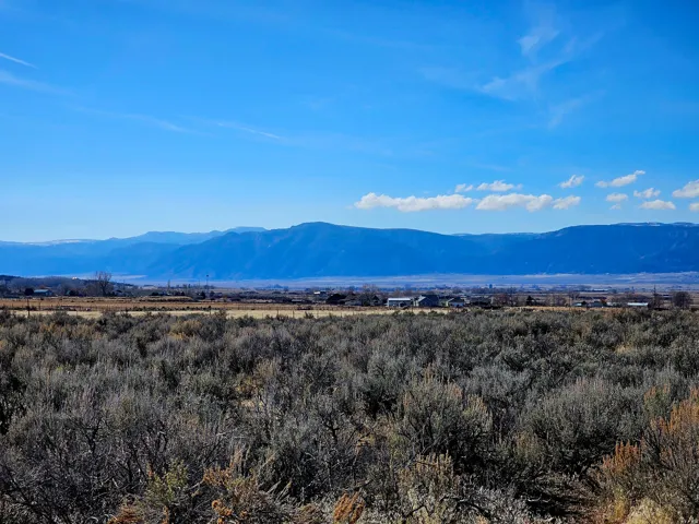 Expansive land with natural vegetation, distant mountains, and clear skies