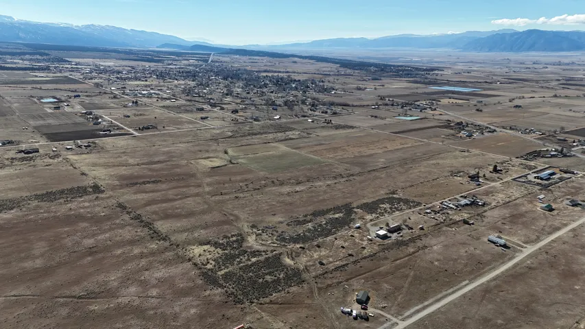 Expansive land parcel featuring open fields, distant mountains, and scattered structures