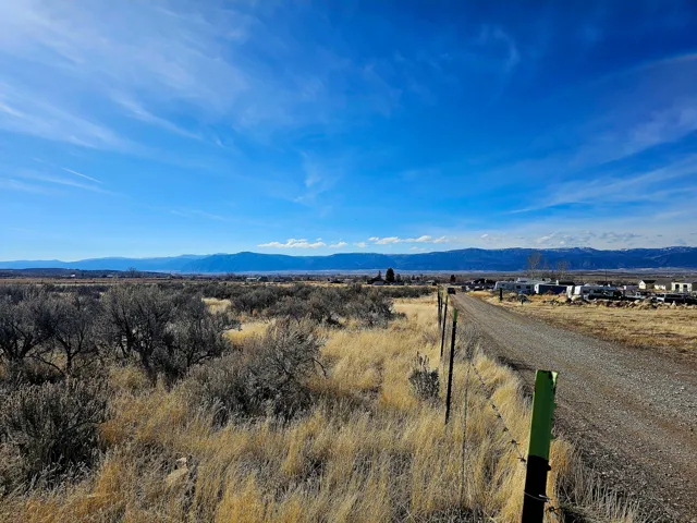 Expansive open terrain featuring natural vegetation, a gravel road, and distant mountain ranges