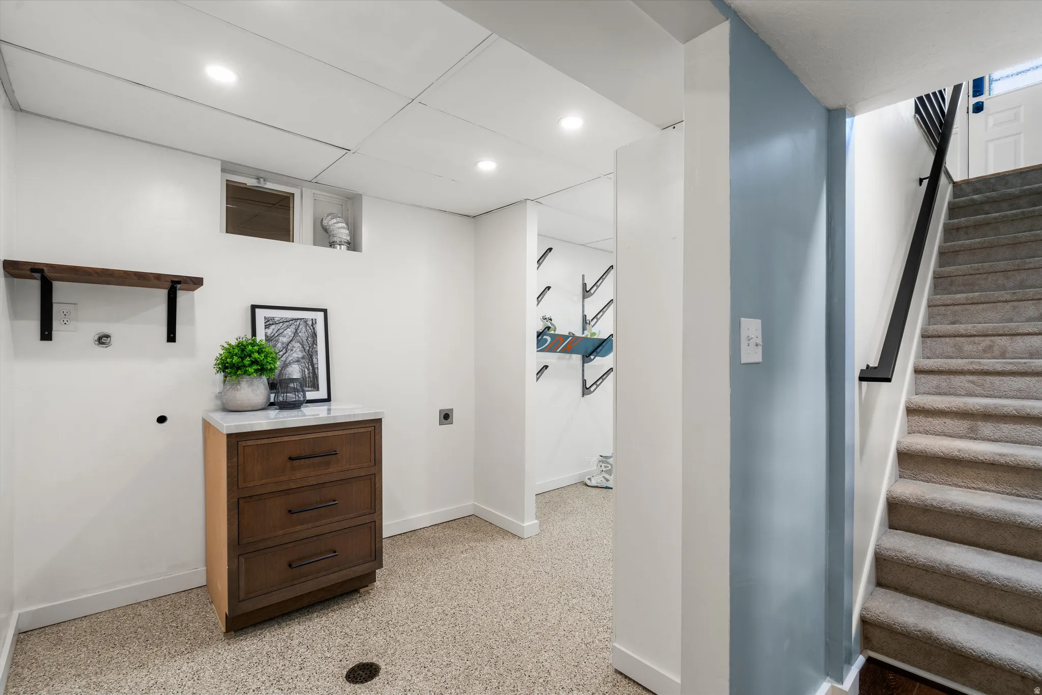 Laundry room Recessed lighting, wood-finish shelving, built-in drawer cabinet with a light-toned countertop, and light-toned epoxy flooring